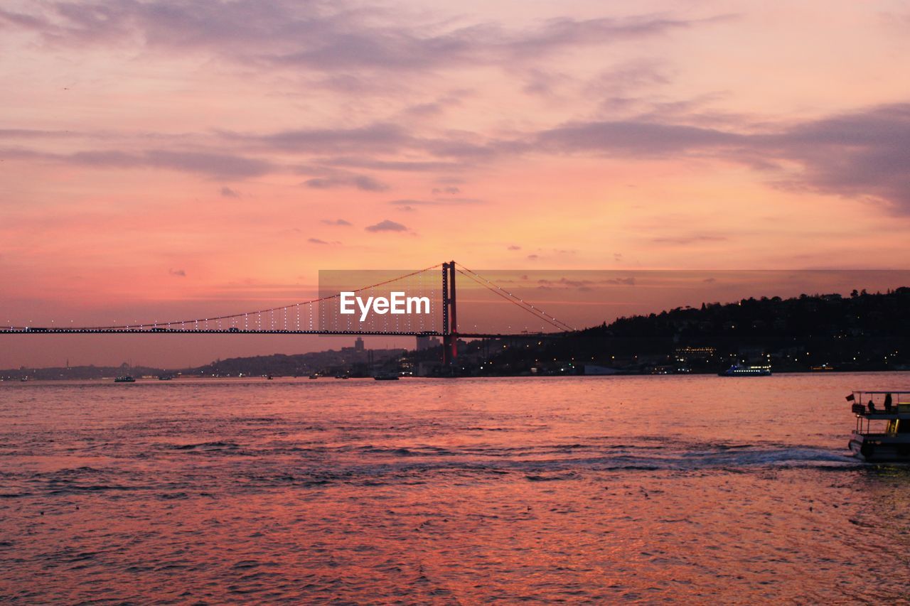 view of suspension bridge over sea against sky during sunset