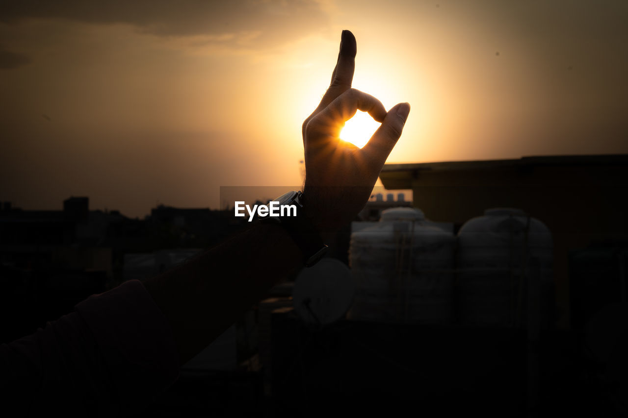 SILHOUETTE HAND AGAINST ORANGE SKY