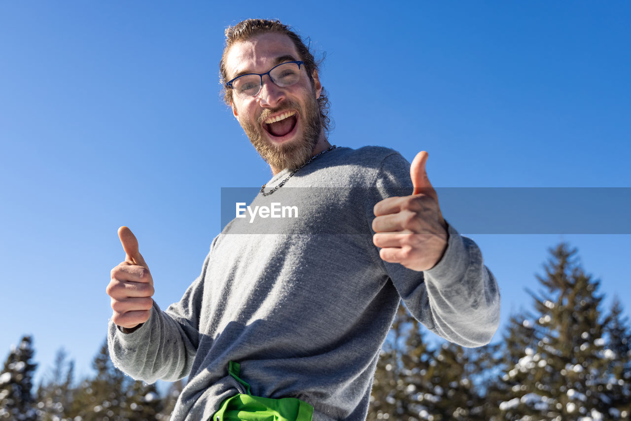 Portrait of smiling young man against blue sky