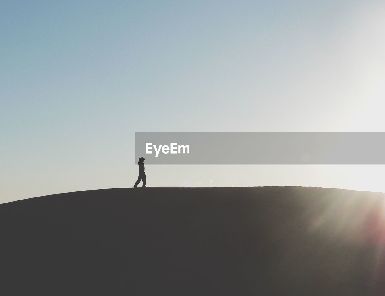 Side view of silhouette man walking on mountain against clear sky