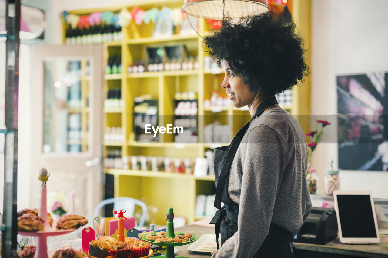 Side view of female barista standing at cafe counter