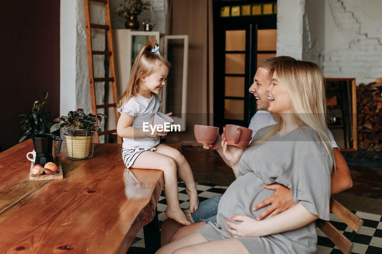 A happy cheerful family with a child is cooking dinner together in the kitchen at home