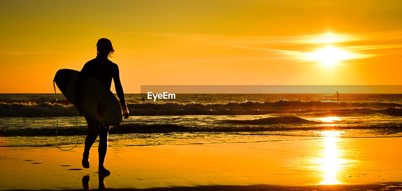 SILHOUETTE MAN STANDING AT BEACH DURING SUNSET