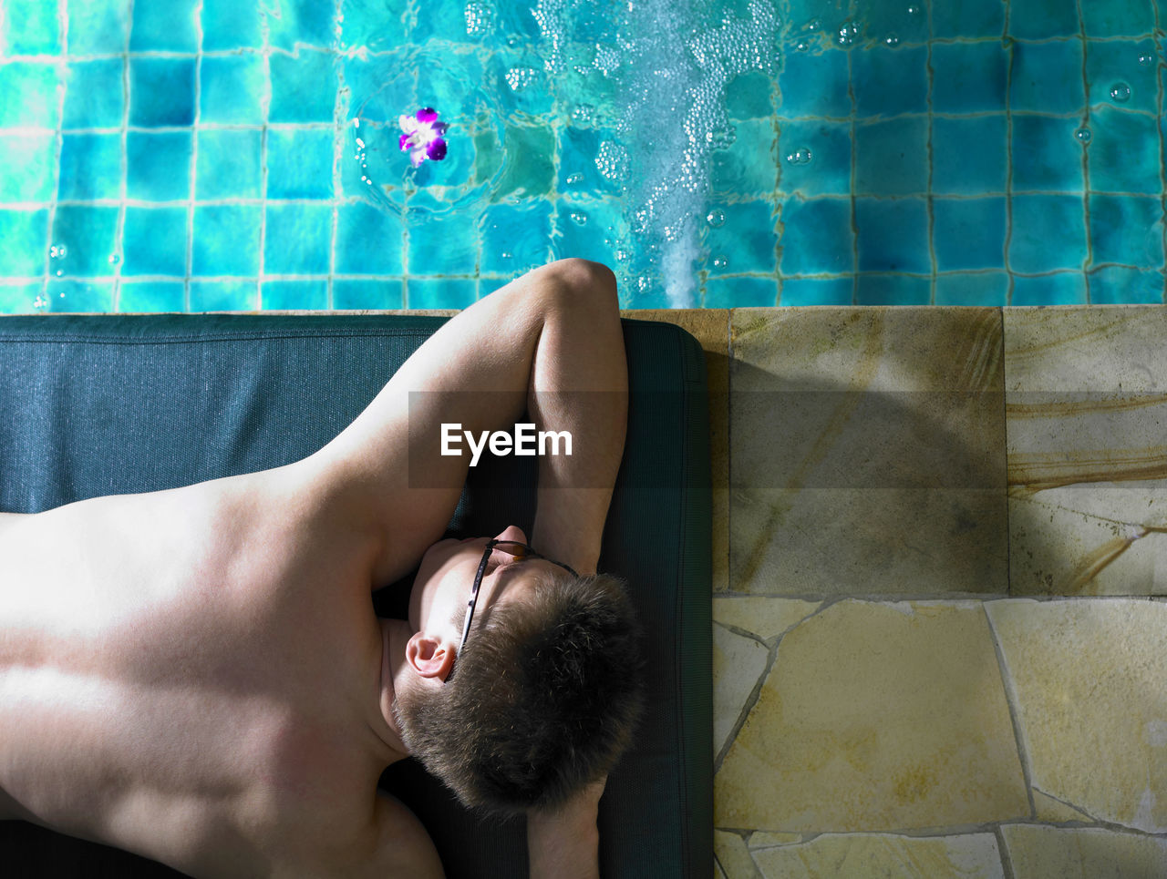 Shirtless man lying on poolside