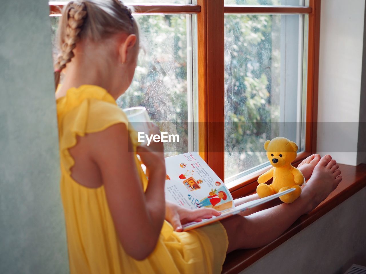 SIDE VIEW OF A GIRL HOLDING TOY AT HOME