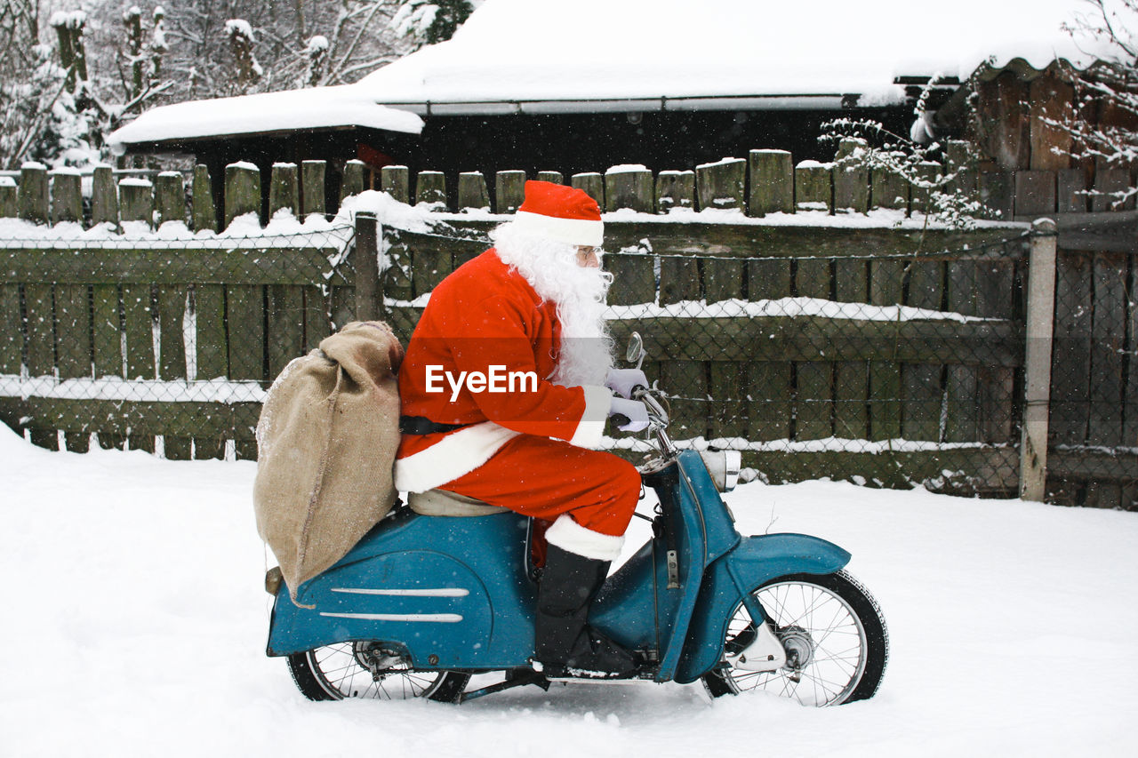 Santaclaus driving moped during winter