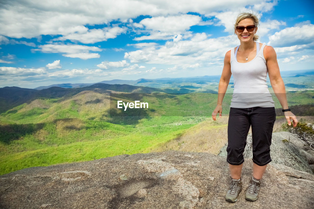 Full length of woman standing on rock against sky