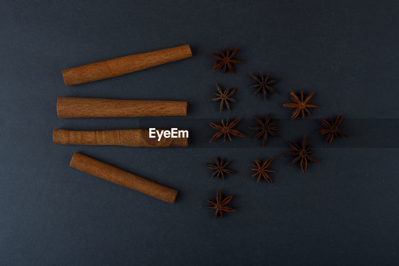 Cinnamon sticks and anise stars flatlay on a dark black background