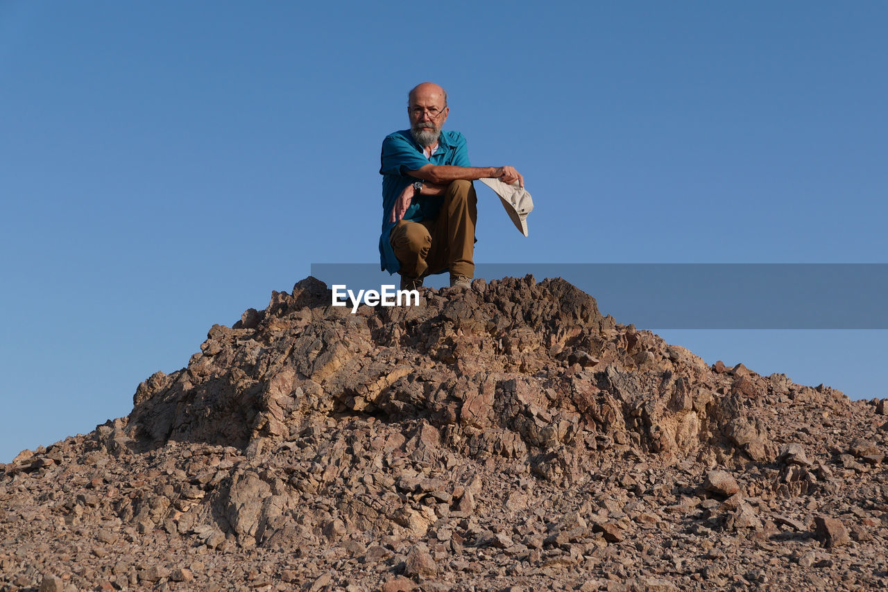 Senior man sitting on rock in the desert 