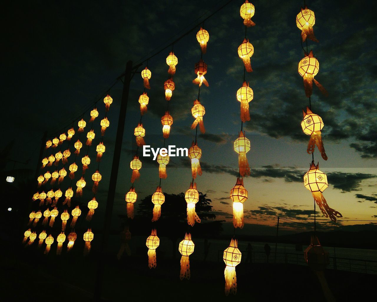 LOW ANGLE VIEW OF ILLUMINATED LANTERNS HANGING AGAINST SKY