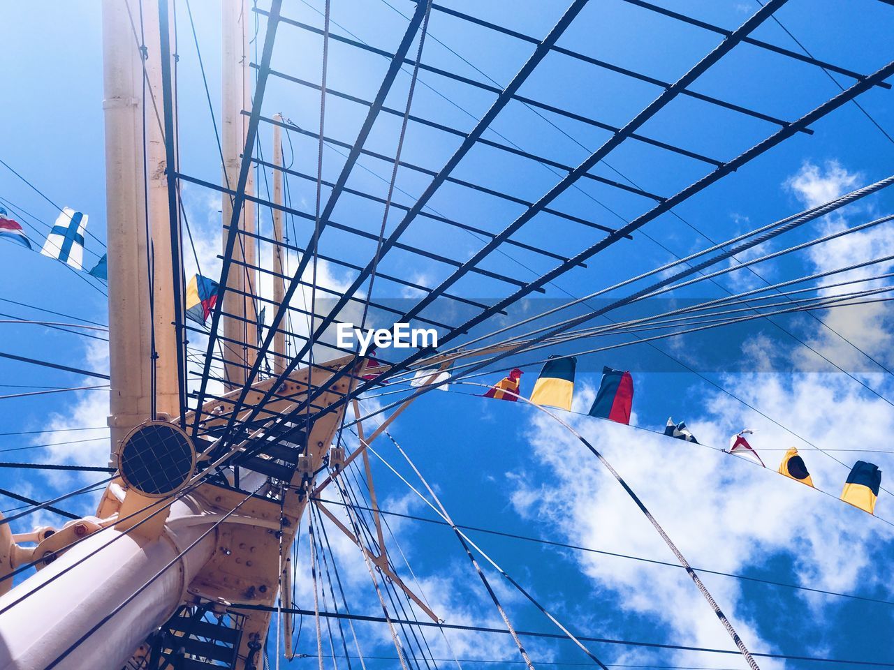 Low angle view of flags hanging against cloudy sky