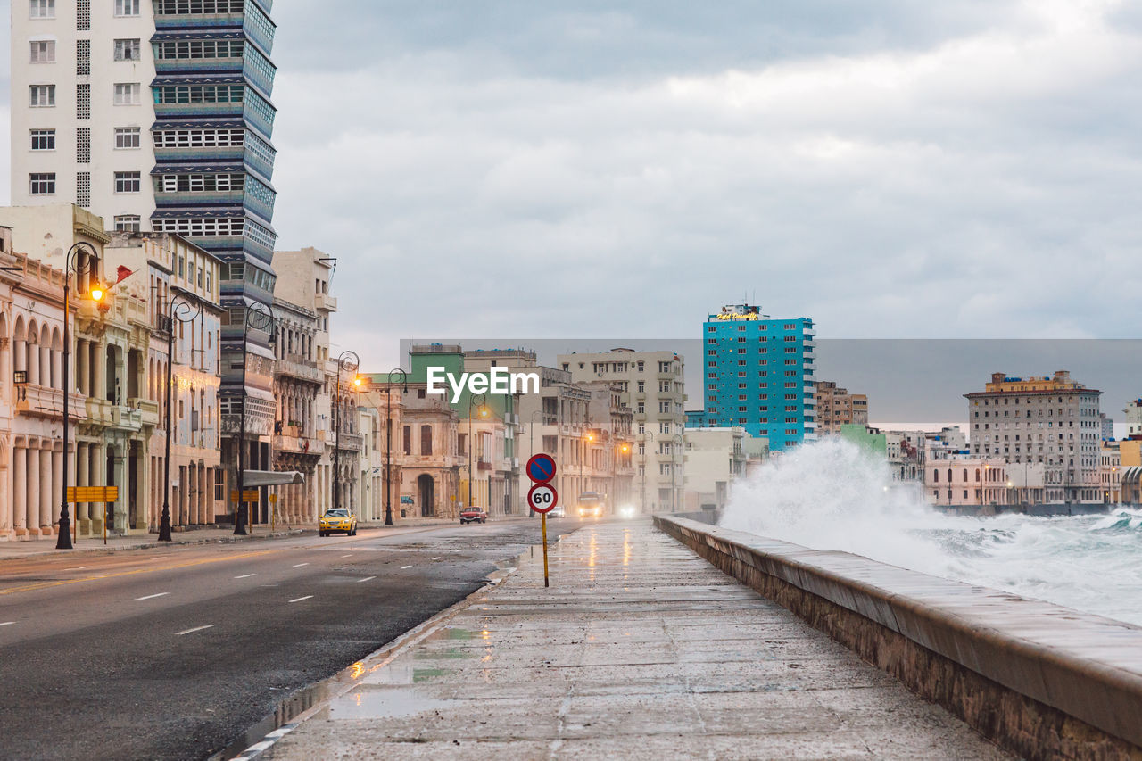 Road amidst buildings in city against sky