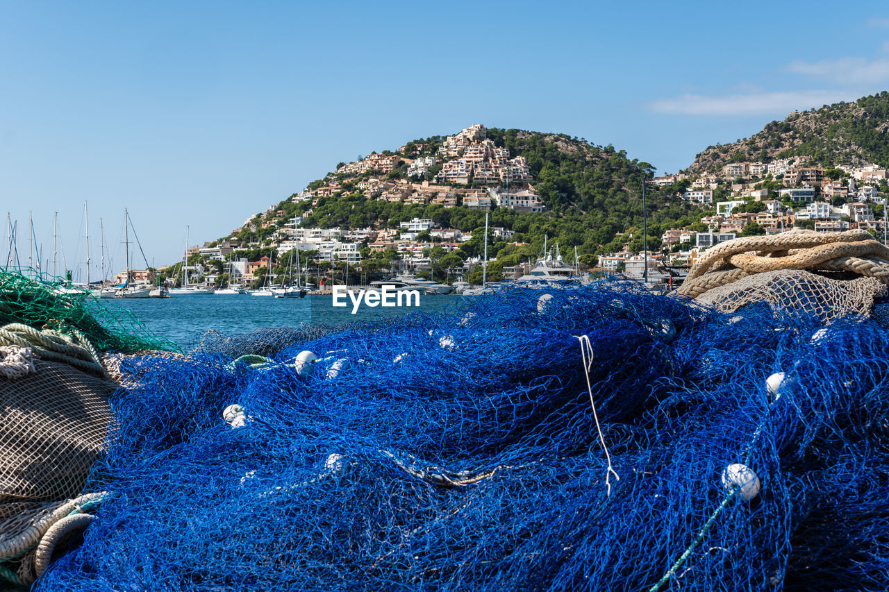 sea, water, fishing industry, fishing, blue, sky, nature, fishing net, coast, land, nautical vessel, harbor, commercial fishing net, no people, transportation, ocean, beach, day, rope, clear sky, outdoors, scenics - nature, travel destinations, shore, coastline, travel, beauty in nature, environment, mode of transportation, mountain, buoy, tranquility, bay, body of water, sunny, sunlight, rock, landscape