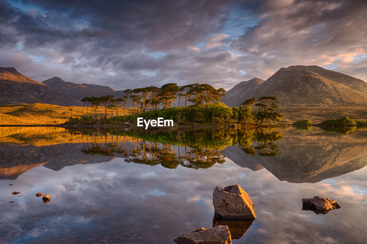 Scenic view of lake and mountains against dramatic sky