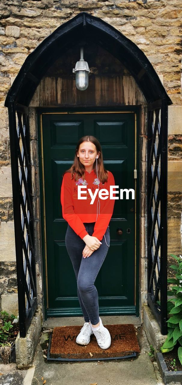 Portrait of teenage girl standing against closed door