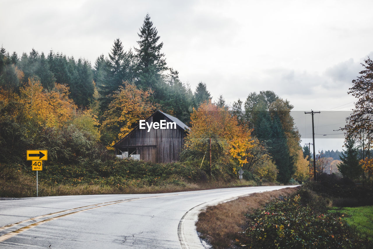 Road amidst trees against sky during autumn