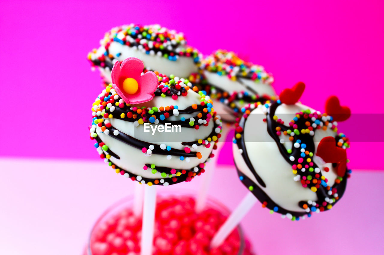 Close-up of lollipops in glass against pink background