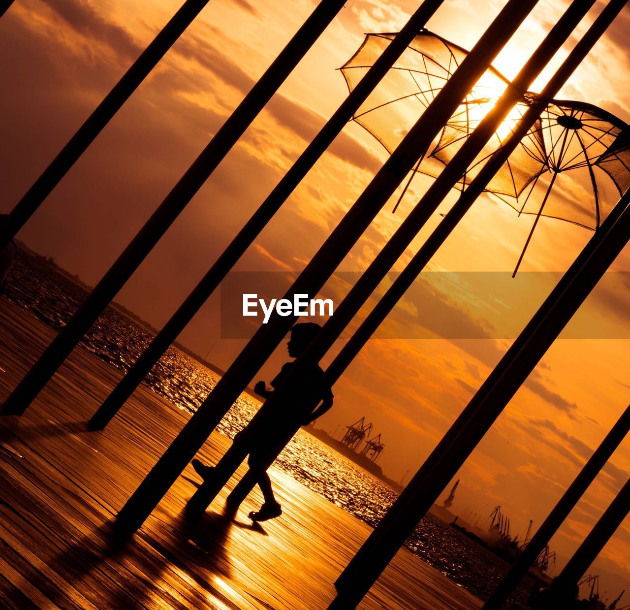 Silhouette of boy walking on boardwalk