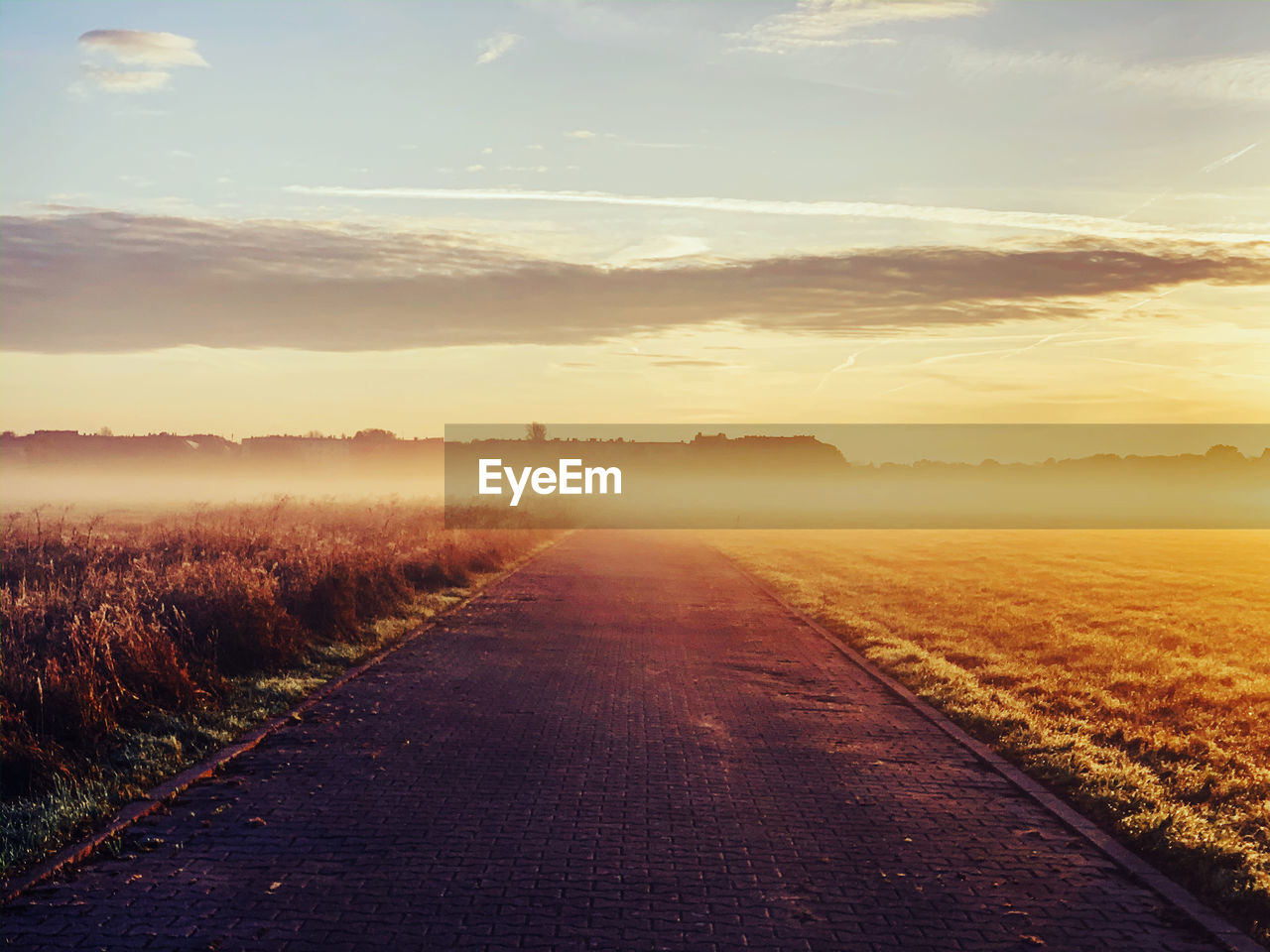 Empty road along landscape during sunset