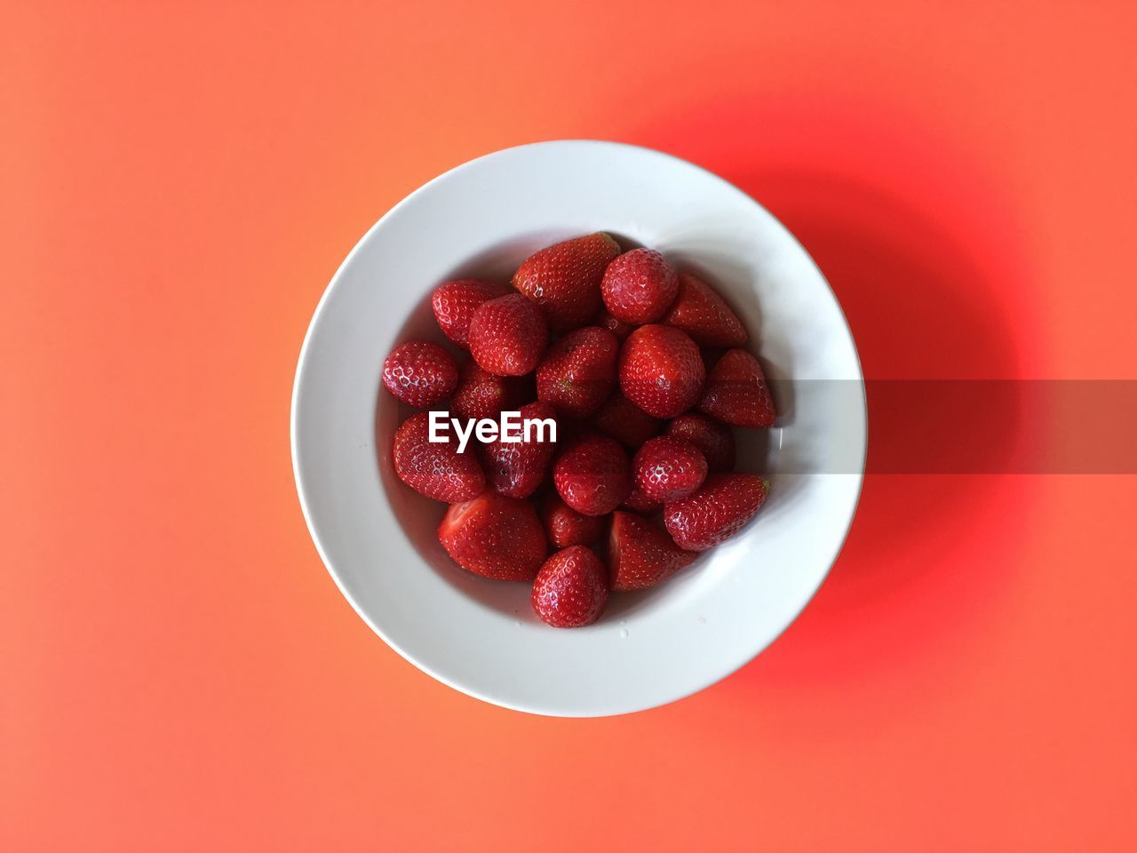 CLOSE-UP OF STRAWBERRIES IN PLATE AGAINST RED BACKGROUND