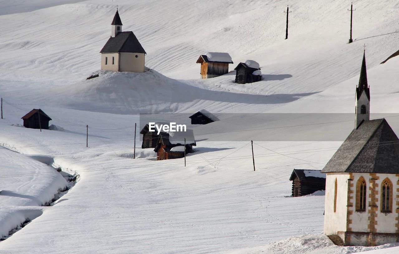 SNOW COVERED HOUSES ON FIELD AGAINST SNOWCAPPED MOUNTAINS