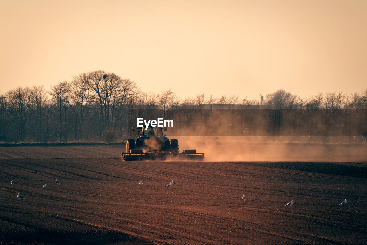 Tractor on agricultural field against clear sky