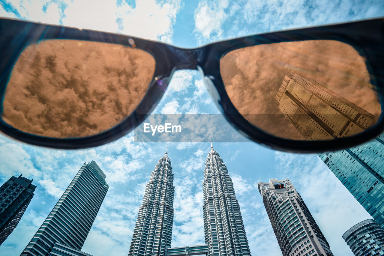 Low angle view of sunglasses against modern buildings in city
