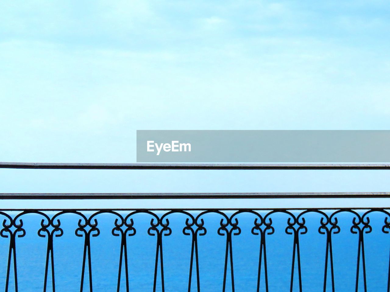 Low angle view of railing against blue sky