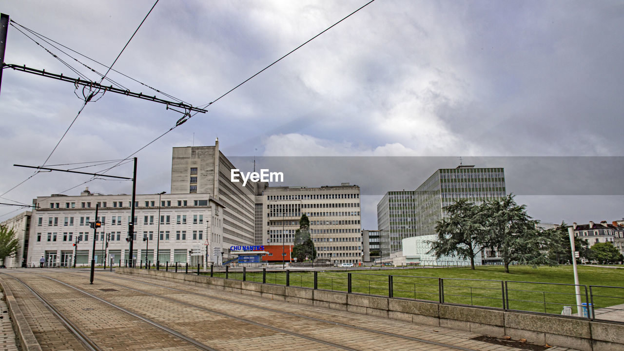 RAILROAD TRACK BY BUILDINGS AGAINST SKY