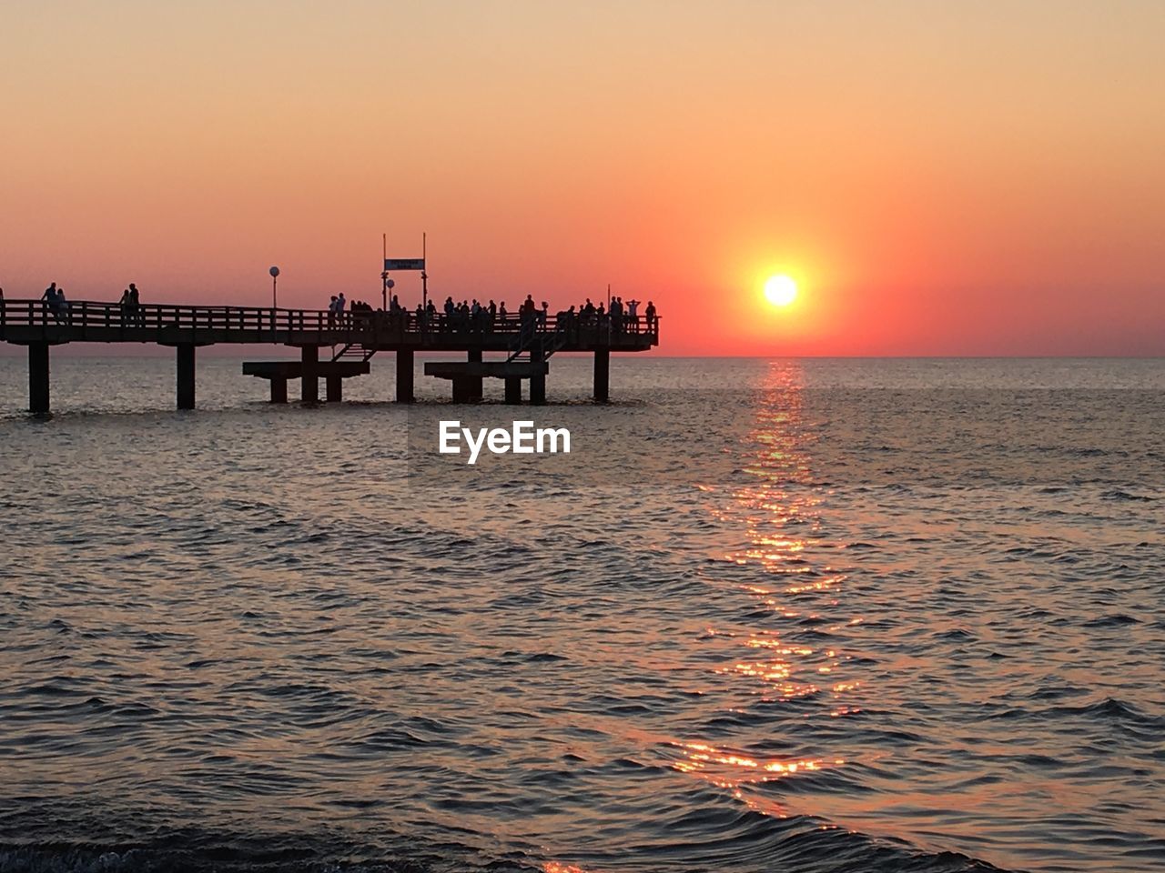 Silhouette pier over sea against sky during sunset