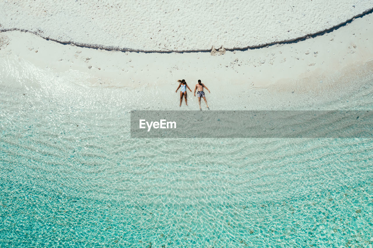 Drone view of couple at beach on sunny day