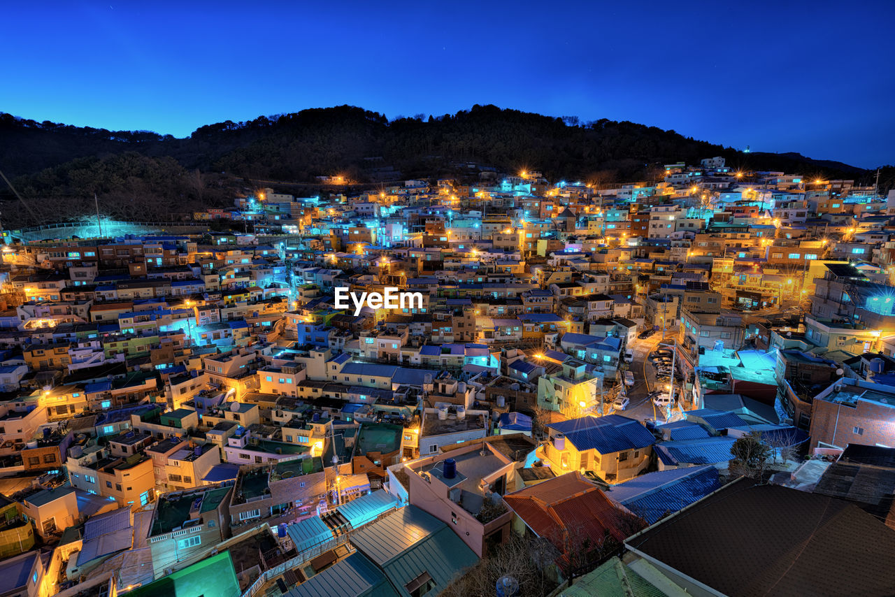 Aerial view of illuminated houses in town against sky at night