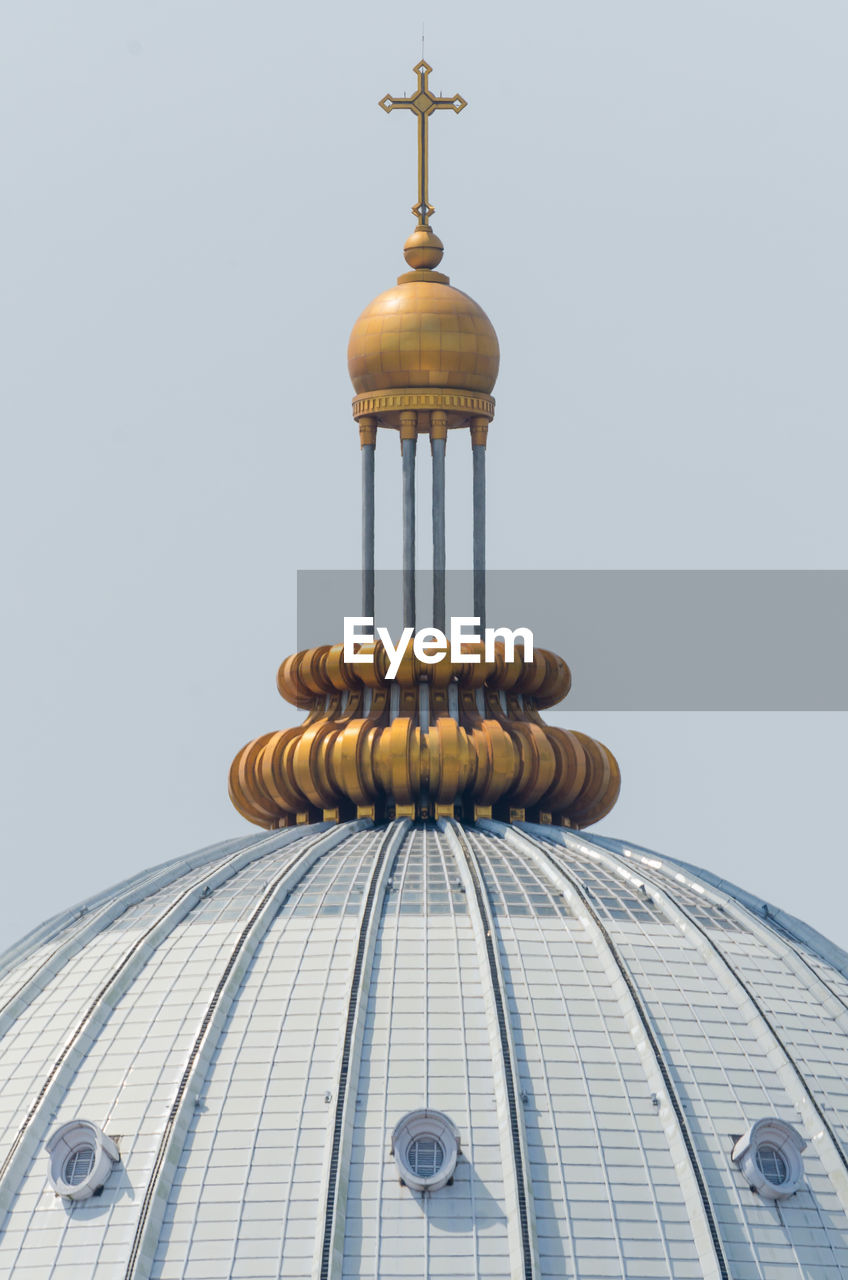 Low angle view of golden cross on building against clear sky