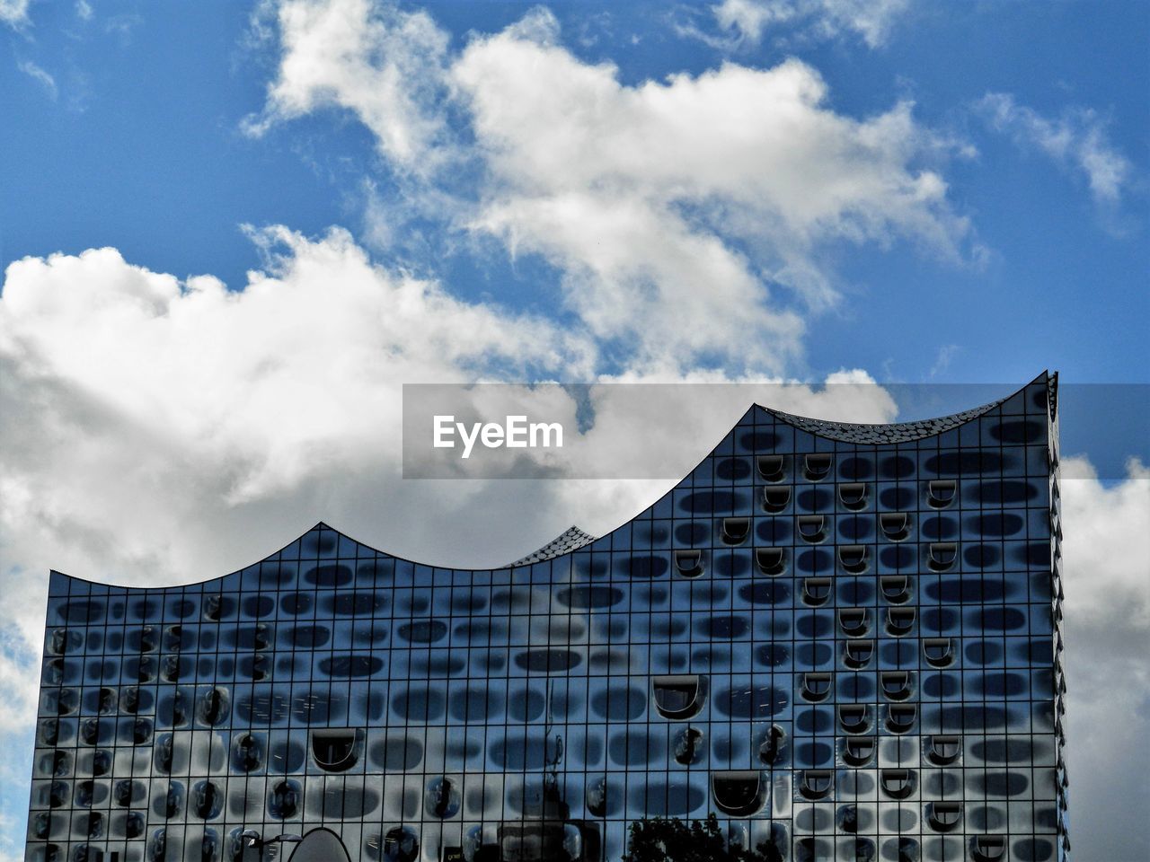 Low angle view of modern building against cloudy sky