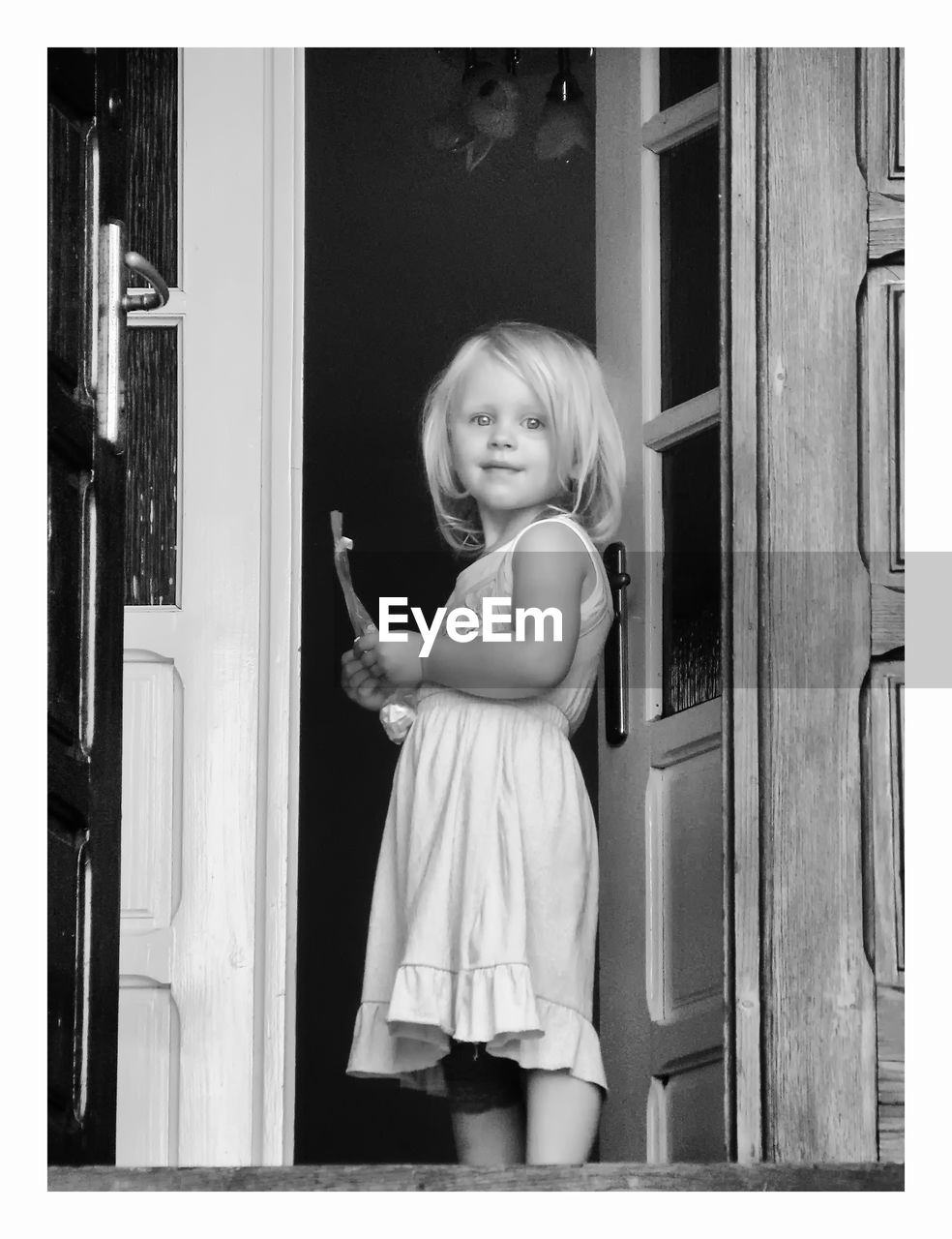 PORTRAIT OF HAPPY GIRL HOLDING DOOR