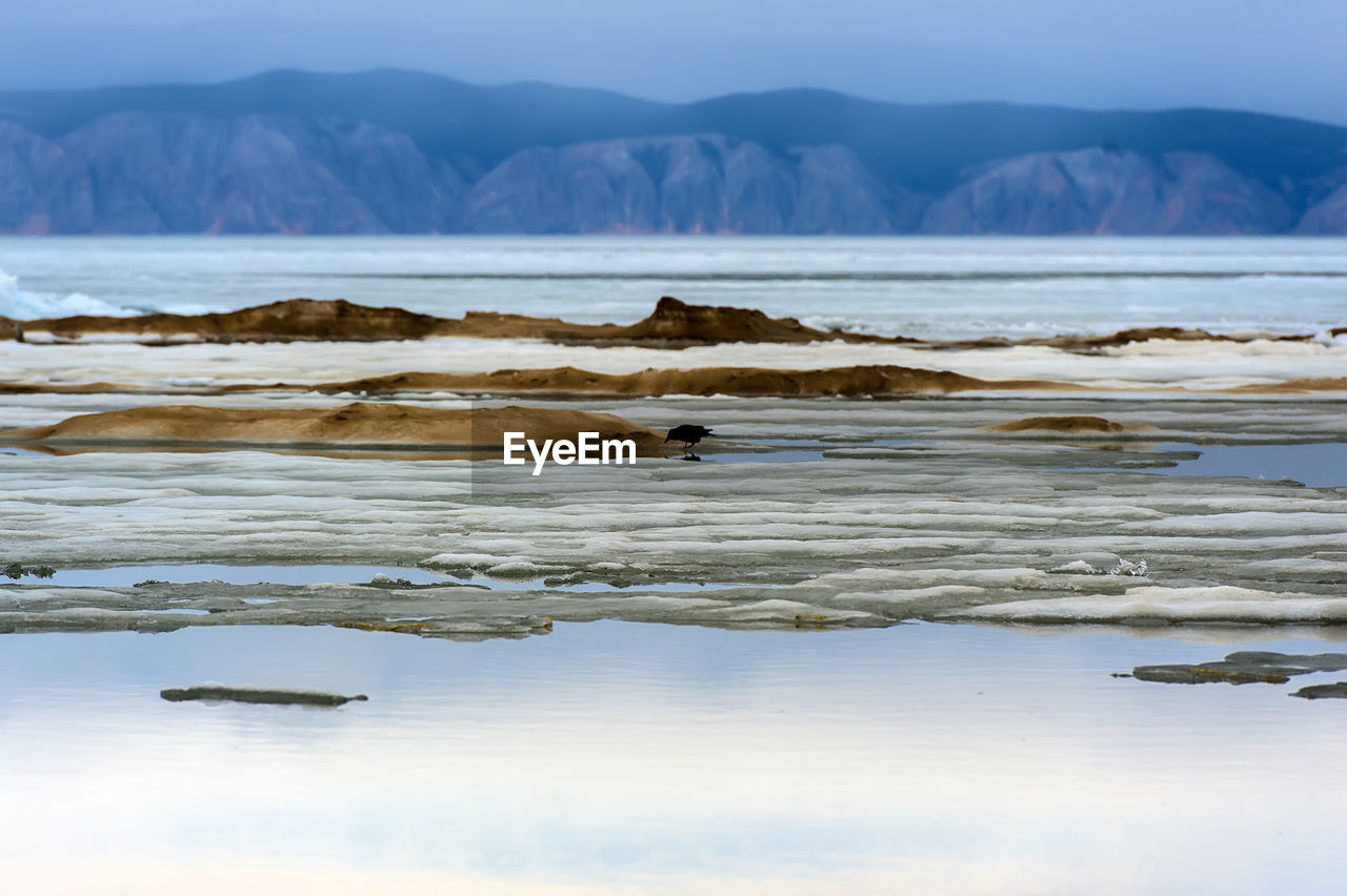 SCENIC VIEW OF SEA AGAINST MOUNTAINS