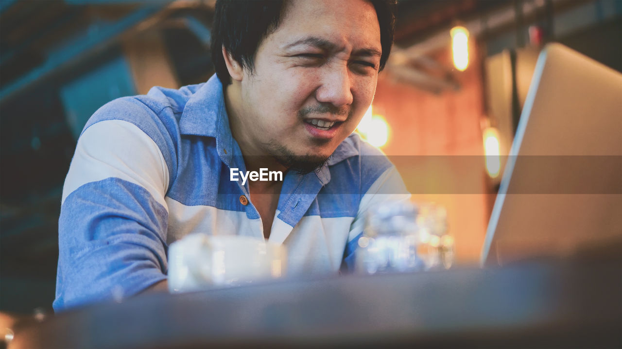 Low angle view of man using laptop in cafe