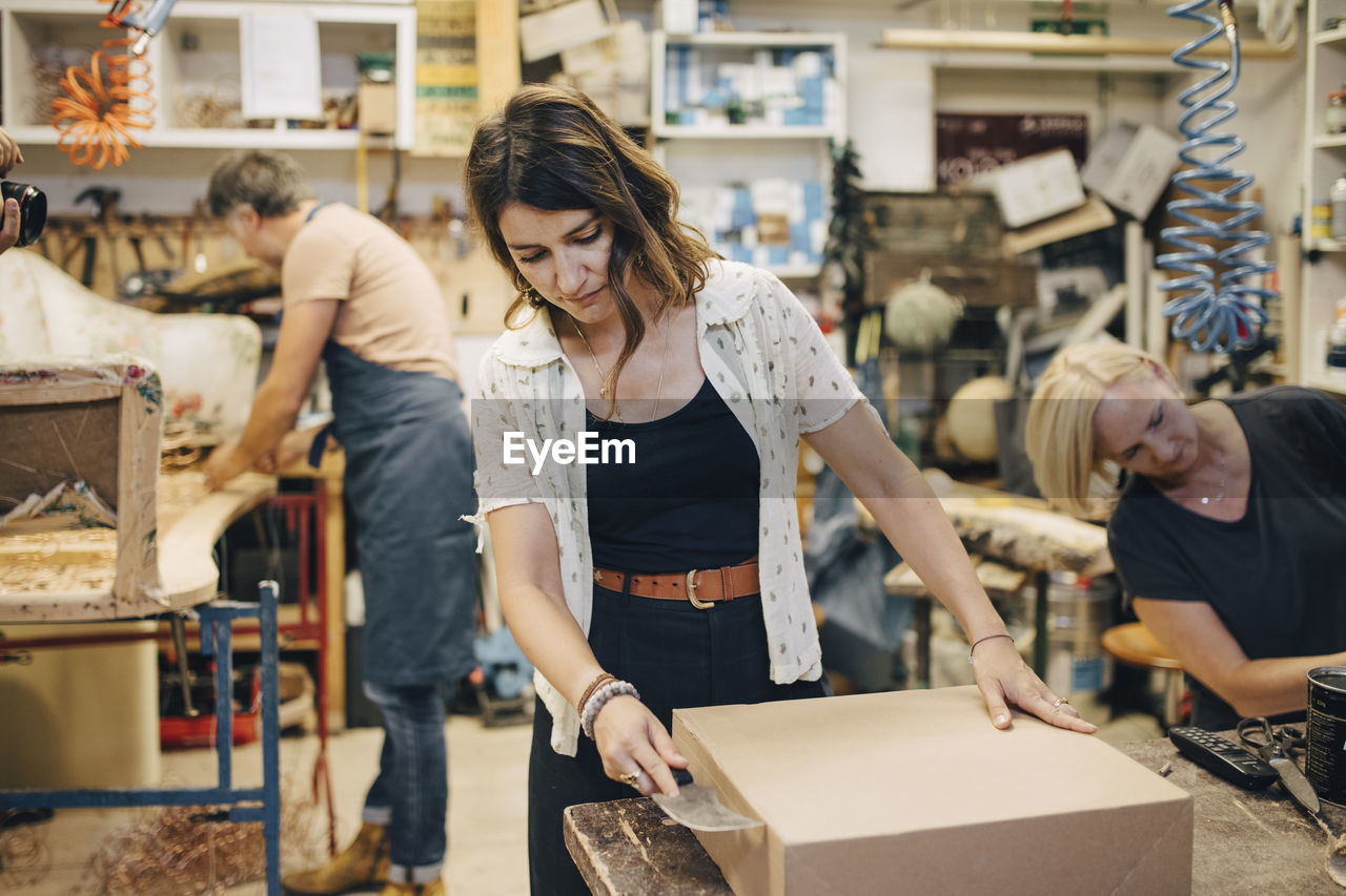 Female and male upholstery workers working in workshop