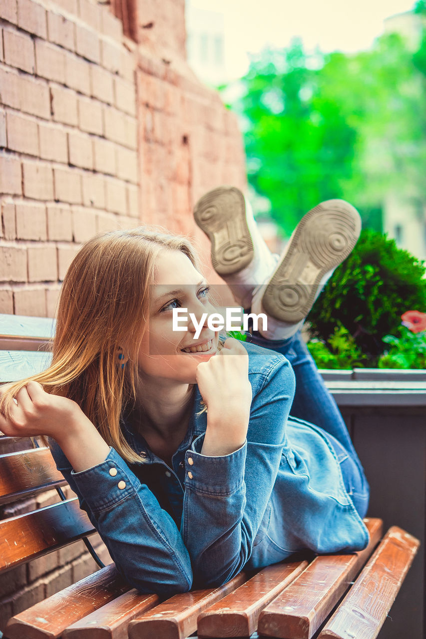 Smiling woman lying down on bench