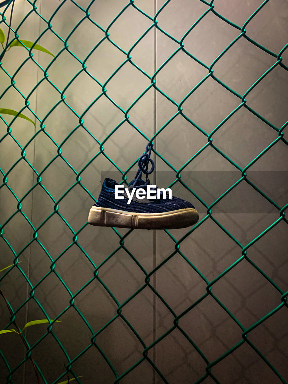 High angle view of shoes hanging on chainlink fence