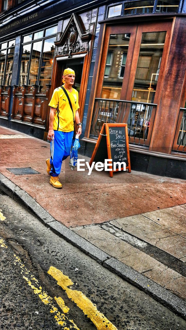 FULL LENGTH PORTRAIT OF MAN STANDING IN CITY