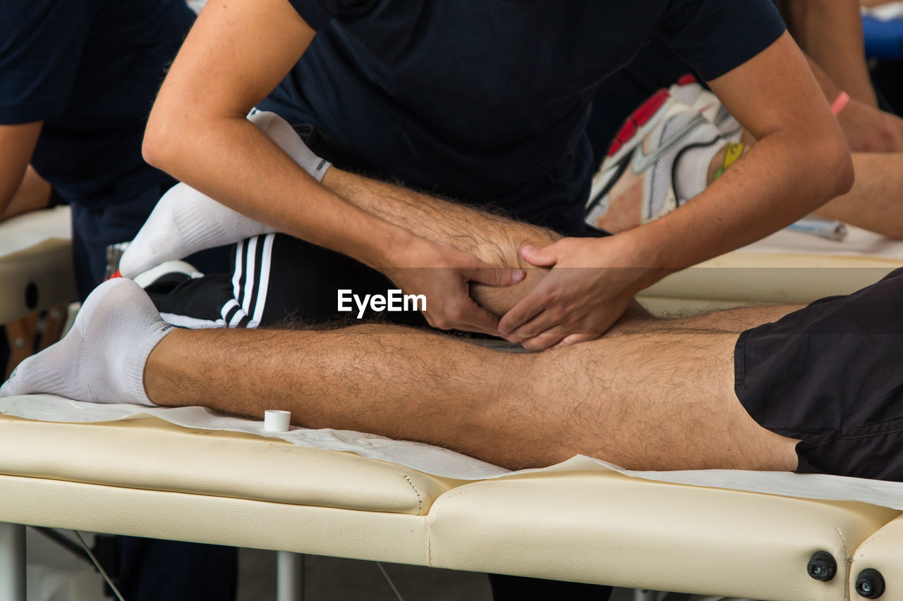 Midsection of man giving massage to athlete lying on bed