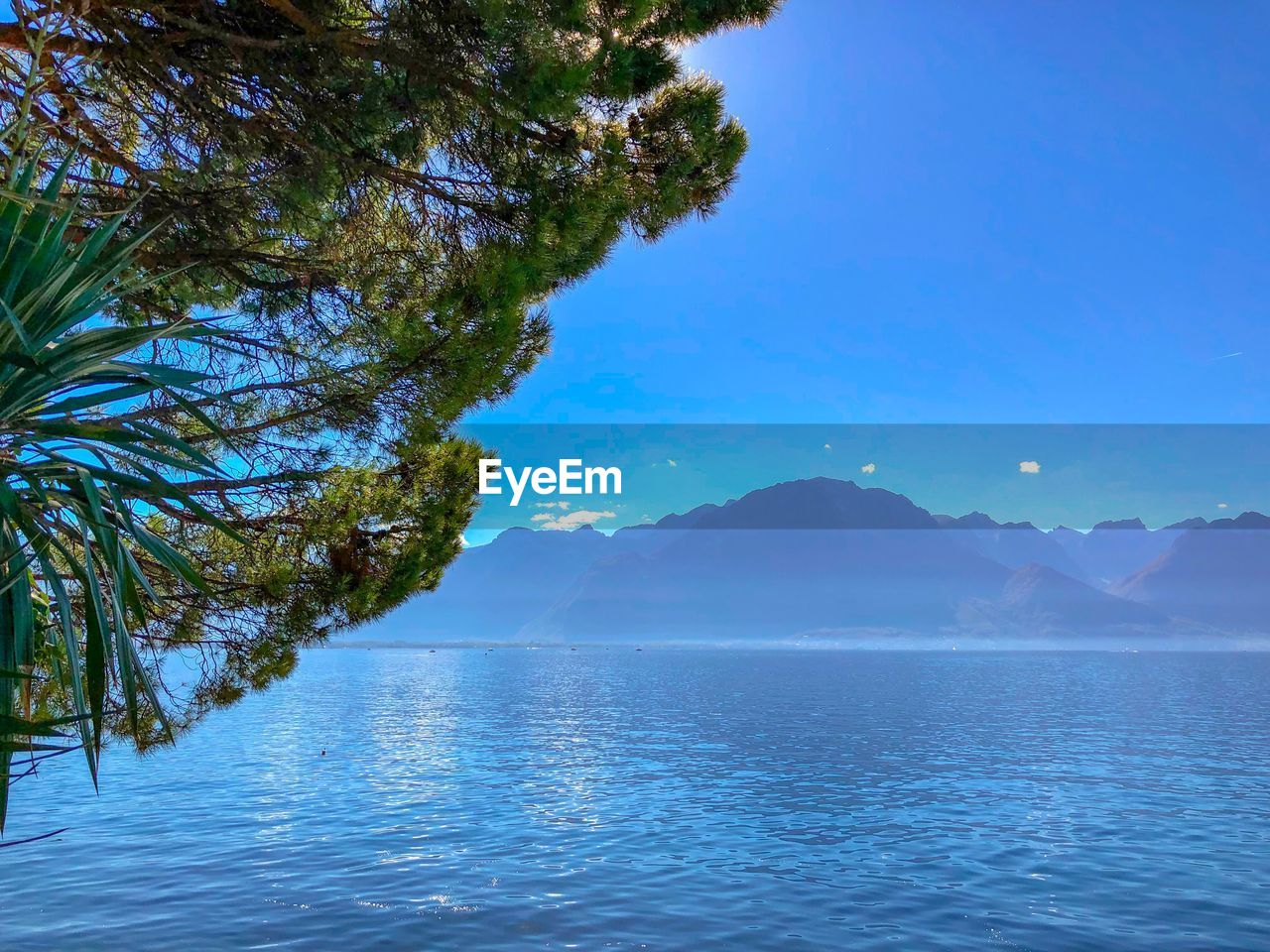 Scenic view of lake and mountains against clear blue sky