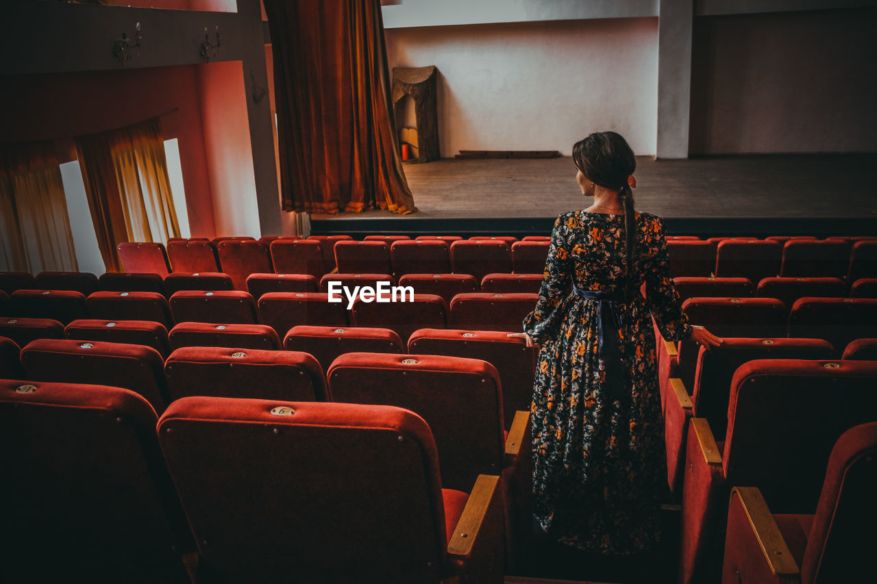 Rear view of woman standing by seats at theater