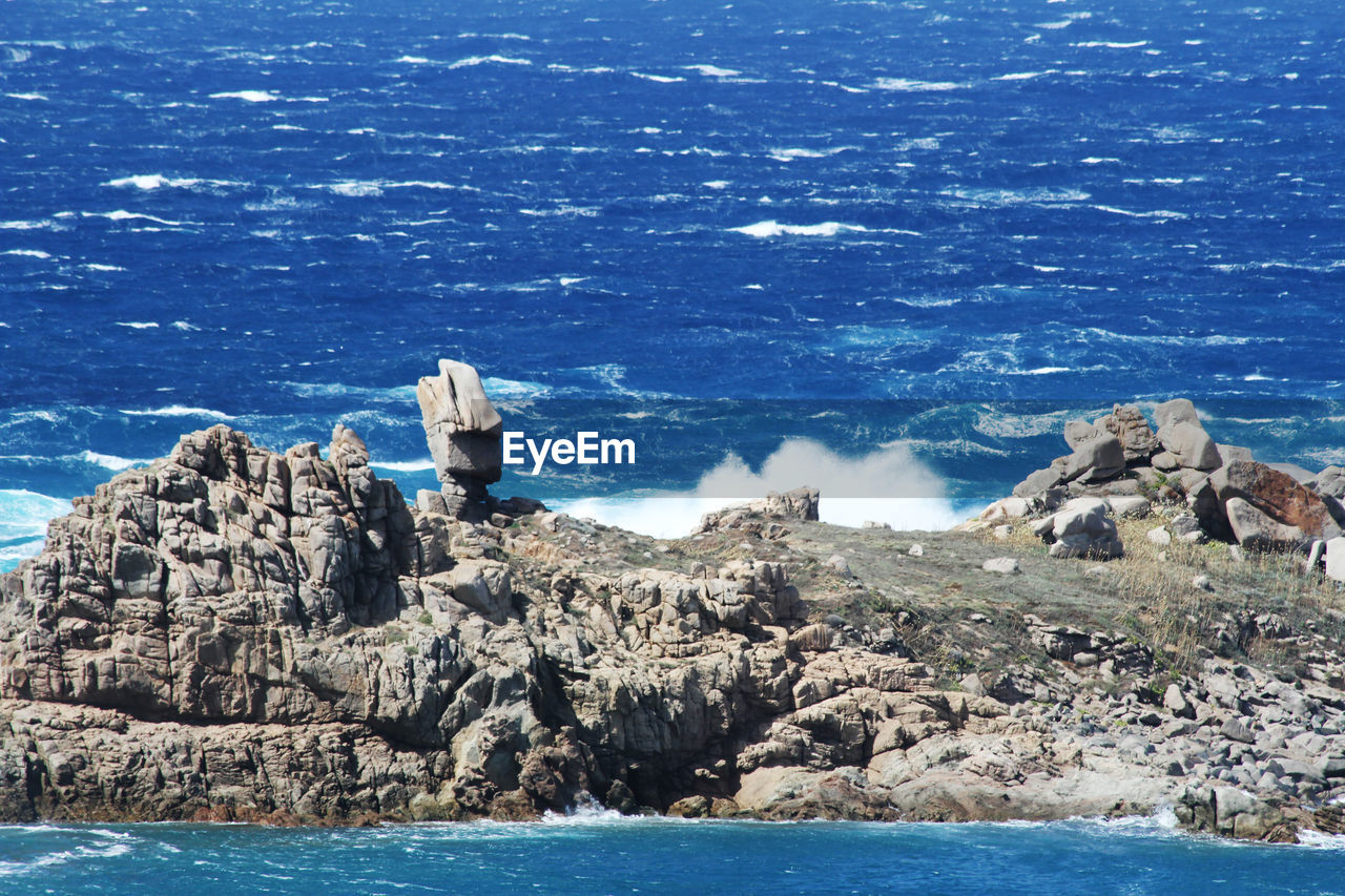 Rock formations on shore against blue sky