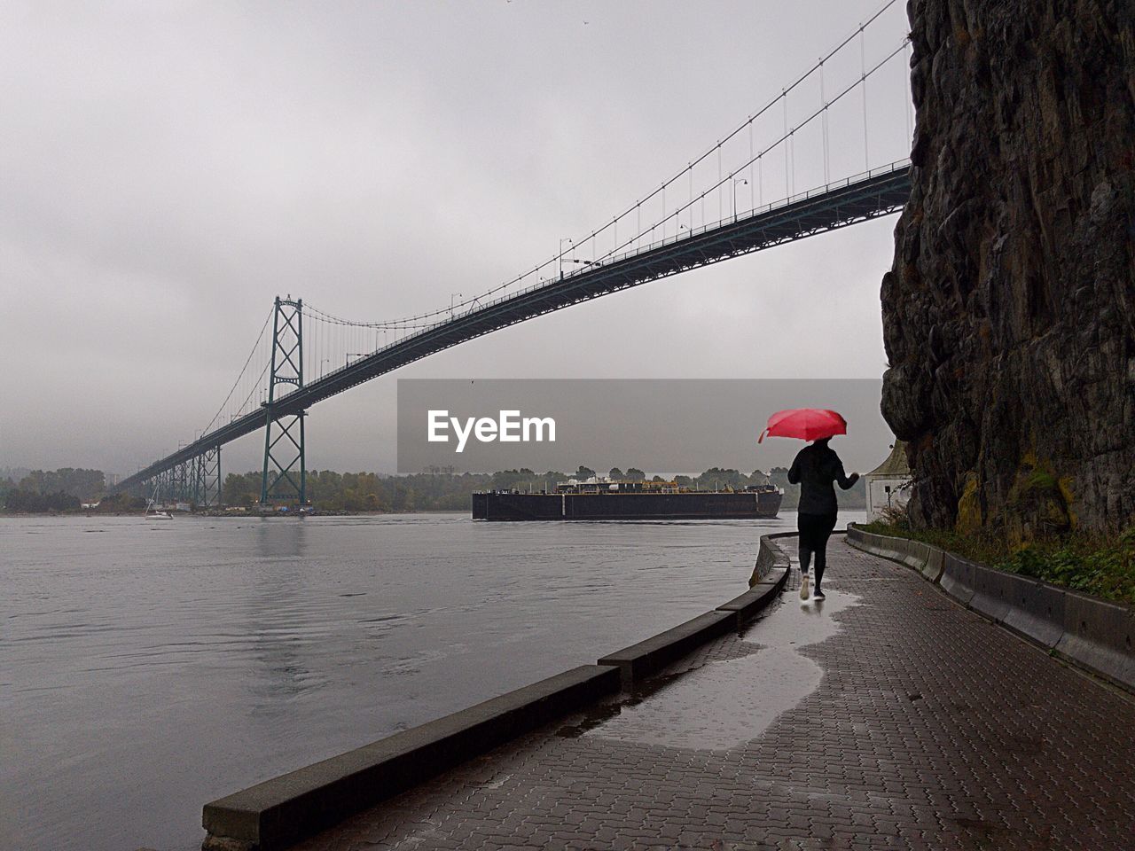 REAR VIEW OF MAN STANDING ON BRIDGE OVER RIVER