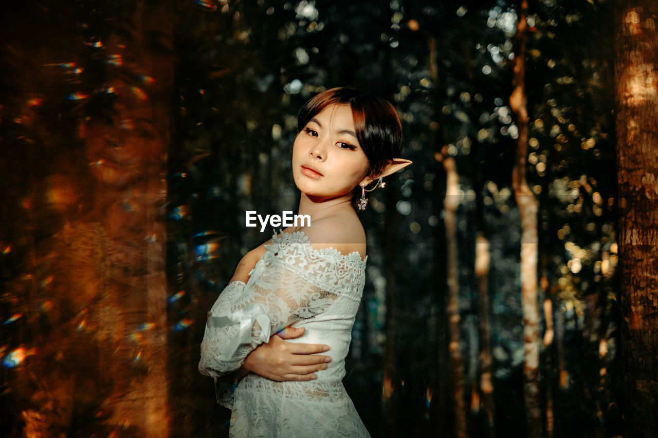 Side view of woman standing on tree trunk