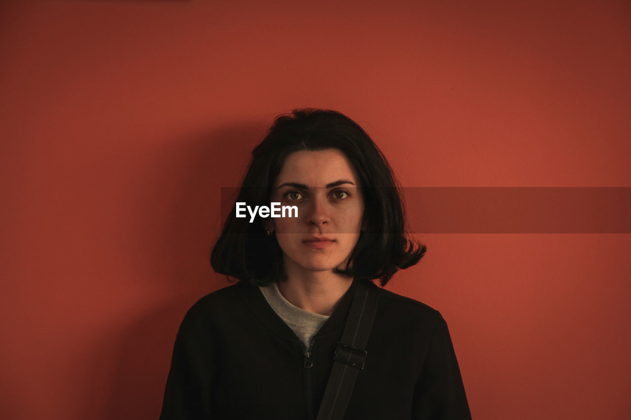 Portrait of young woman against orange background