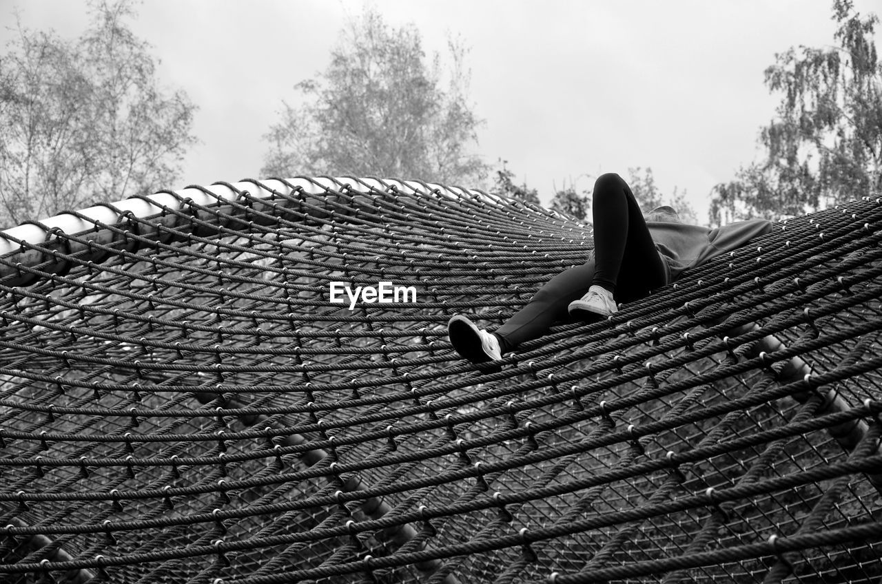 Low angle view of woman lying on net at playground
