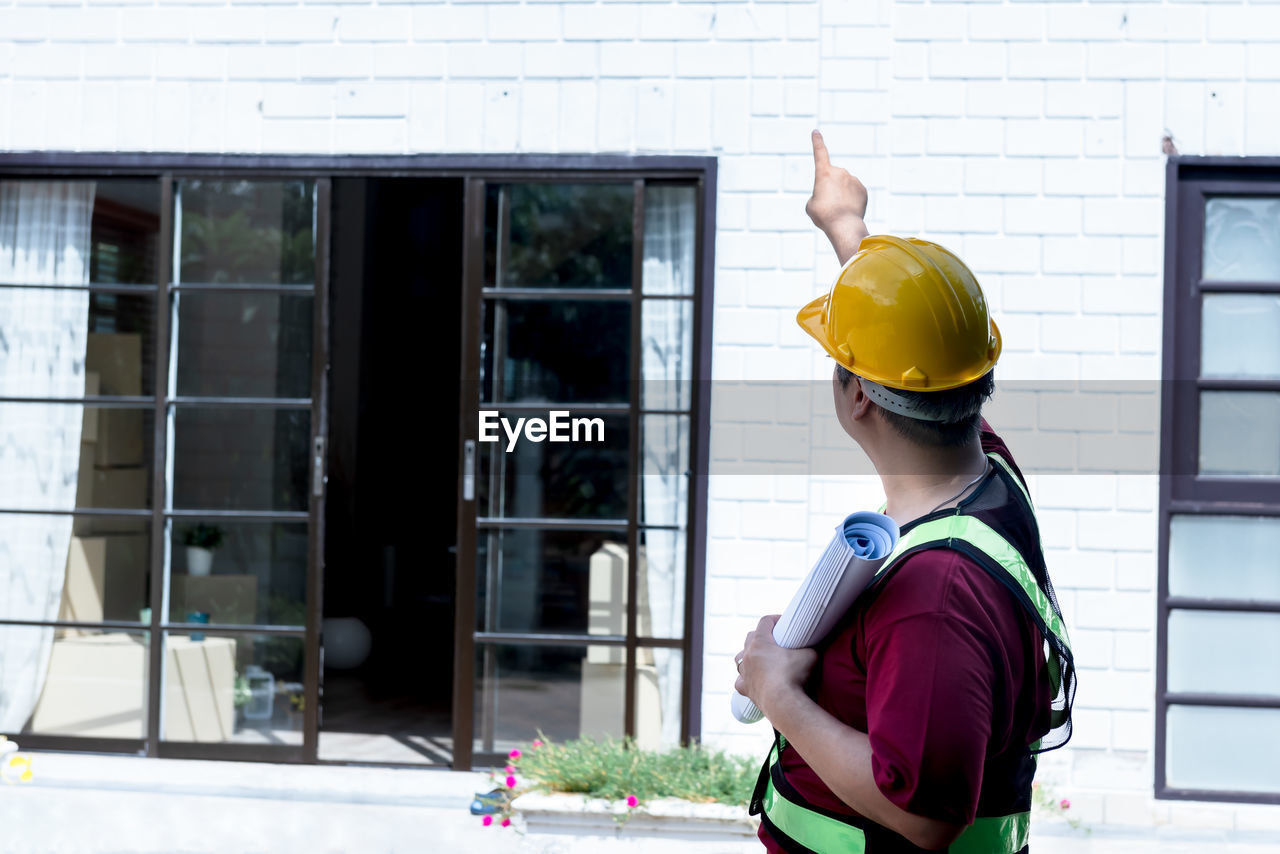 FULL LENGTH REAR VIEW OF WOMAN STANDING AGAINST WINDOW